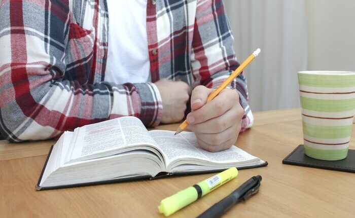 Joven con libro y lápices sobre una mesa, estudiando
