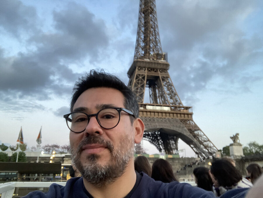 Selfie del estudiante de Doctorado en Educación UC Leandro Silva con la Torre Eiffel de fondo. 